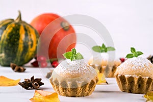 Homemade baking in autumn style. Delicious cupcakes on a wooden board with cinnamon sticks, anise stars, pumpkins