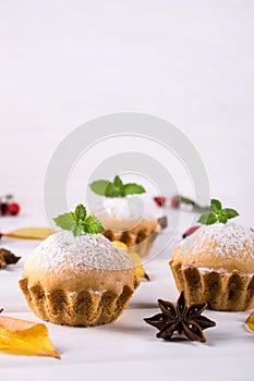 Homemade baking in autumn style. Delicious cupcakes on a wooden board with cinnamon sticks, anise stars, pumpkins