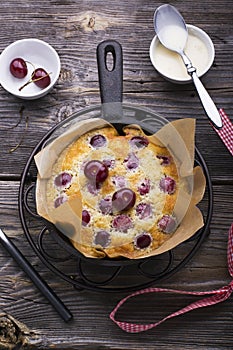 Homemade baking. Fresh golden flavored cake with cherries in a black cast iron skillet is watered condensed milk. View