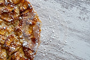 Homemade baking. Freshly baked apple pie on a light wooden background sprinkled with icing sugar