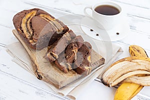 Homemade banana bread on a wooden board on a white table. The concept of breakfast and dietary nutrition.