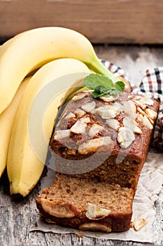 Homemade banana loaf cake with fresh bananas on wooden table