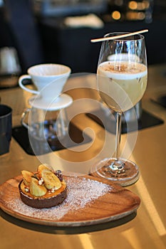 Homemade Banoffee cake and coffee latte in tall glass. English traditional pie.