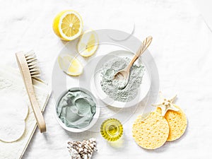 Homemade beauty facial mask. Clay, lemon, oil, facial brush - beauty products ingredients on light background