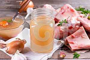 Homemade beef bone broth with natural collagen. Bouillon in a glass mug and raw beef bone photo