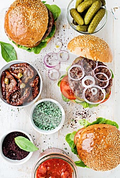 Homemade beef burgers with onion, pickles, vegetables, sun-dried tomatoes, spices