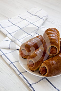 Homemade beef sausage kolache on a white plate on a white wooden background, low angle view. Copy space