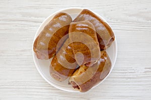 Homemade beef sausage kolache on a white plate on a white wooden background, top view. Close-up