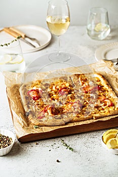 Homemade Belgian style seafood pizza, flammekeuche, served on table with white wine