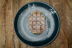 Homemade Belgian waffle on a plate. With powder sugar on it. Top view
