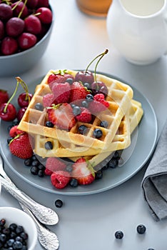 Homemade belgian waffles with berries on gray table. Healthy breakfast concept