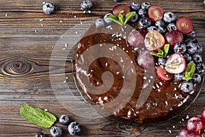 Homemade berry pie close up ,  chocolate cake with fresh berries red grapes and blueberries, mint on a wooden