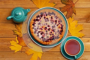 Homemade berry pie and cup of tea on wooden table.