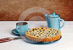 Homemade berry pie with ricotta and black currant on white wooden table.