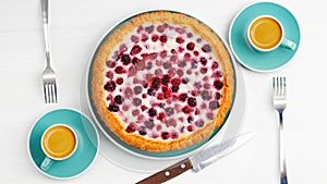 Homemade berry pie and two cups of coffee espresso on white wooden table.