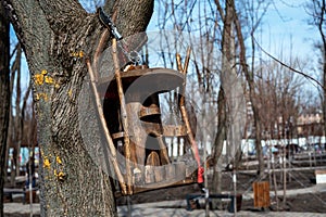 Homemade birdhouse in the park on a tree hanging on a chain