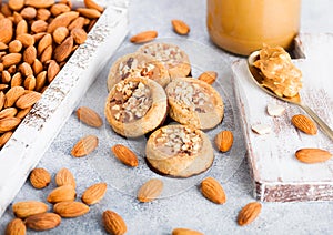Homemade biscuit cookies with almond nuts and peanut butter on marble board on white kitchen table background. Almonds in wooden