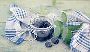 Homemade blackberries jam in a glass jar over rustic wooden table. Healthy food concept. Organic berries. Soft focus