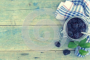 Homemade blackberries jam in a glass jar over rustic wooden table. Healthy food concept. Organic berries. Top view