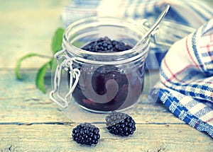 Homemade blackberries jam in a glass jar over rustic wooden table. Healthy food concept. Organic berries. Top view