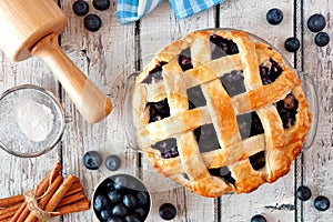 Homemade blueberry pie, top view baking scene over a white wood background