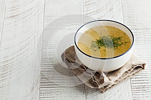 Homemade bone broth in a white bowl on a wooden background. The concept of healthy eating. Copy space