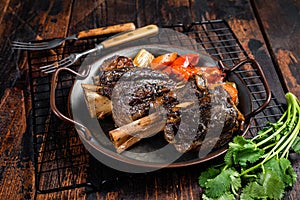 Homemade Braised Lamb Shanks with Sauce and Herbs in a steel tray. Wooden background. Top view