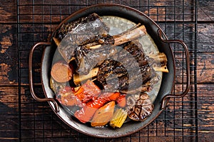 Homemade Braised Lamb Shanks with Sauce and Herbs in a steel tray. Wooden background. Top view