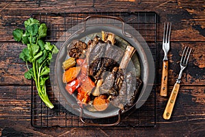 Homemade Braised Lamb Shanks with Sauce and Herbs in a steel tray. Wooden background. Top view