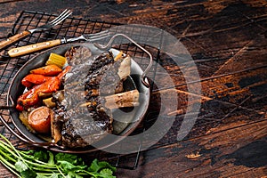Homemade Braised Lamb Shanks with Sauce and Herbs in a steel tray. Wooden background. Top view. Copy space
