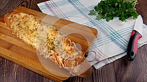 Homemade bread - baguette with cheese on top on a cutting board on a white towel