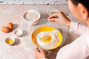 Homemade bread baking. closeup woman hands adding salt in flour, dough preparation in bright kitchen with marble countertop