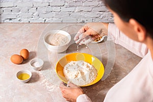 Homemade bread baking. closeup woman hands mixing ingredients for dough preparation in bright kitchen with marble countertop