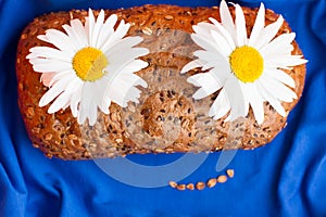 Homemade bread with cereals and chamomille smile face on a blue background