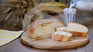 Homemade bread, milk and ripe ears of rye on a wooden background