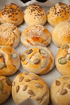 The homemade bread rolls with sesame seeds hamburger with sesame, pumpkin, flax, sunflower seeds on the tray, concept of burger