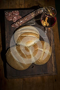 homemade bread, salami, glass of wine, and knife