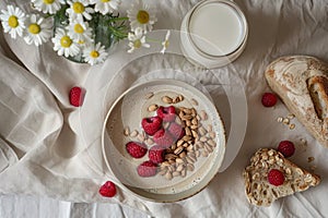 Homemade bread, smoothie bowl with granola and berries for healthy breakfast, flowers, milk glass, elevated luxurious