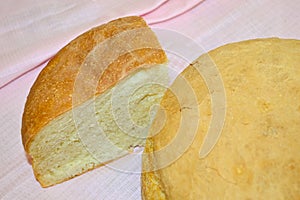 Homemade bread - whole and a piece, on the background of a pink tablecloth