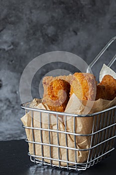Homemade breaded fish fingers in a wire basket with greaseproof paper.