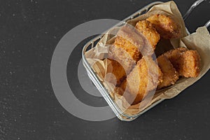 Homemade breaded fish fingers in a wire basket with greaseproof paper.