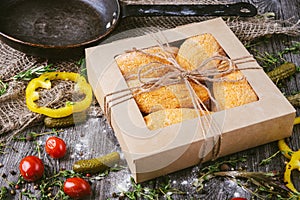 Homemade breaded uncooked cutlets in a box on a wooden table in a rustic style. Healthy food.