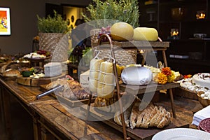 Homemade breads and assorted cheeses exposed on the wooden table