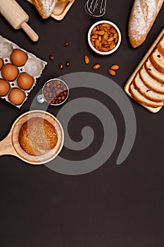 Homemade breads or bun, croissant and bakery ingredients, flour, almond nuts, hazelnuts, eggs on dark background, Bakery