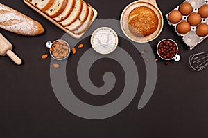 Homemade breads or bun, croissant and bakery ingredients, flour, almond nuts, hazelnuts, eggs on dark background, Bakery backgroun