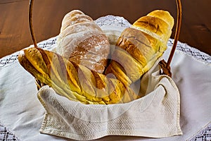 Homemade breads. different types of home-made breads in basket on white tablecloth on wooden table