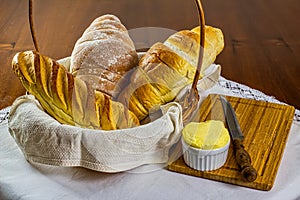 Homemade breads. different types of home-made breads in basket with wooden cutting board, knife and porcelain ramekin with butter