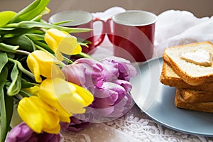 Homemade breakfast in bed. Toast with peanut butter, a cup of coffee and tulips. Good morning