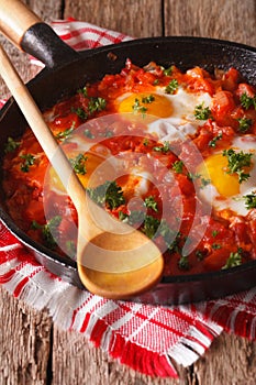 Homemade breakfast shakshuka of fried eggs with tomato close-up. Vertical