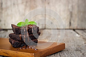 Homemade brownie served with chocolate fudge. Sweet dessert on wooden background